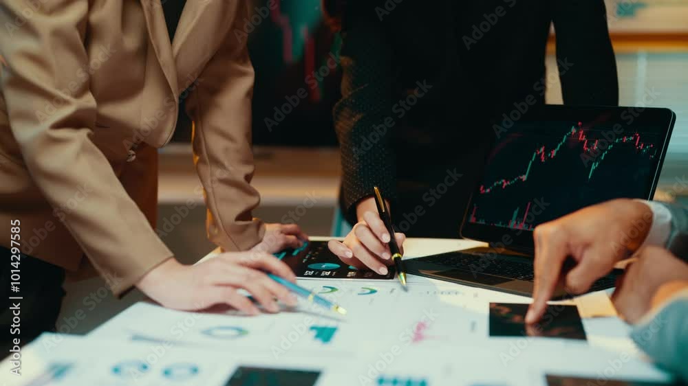 Poster Business teams work late, analyzing financial data and charts on a laptop while collaborating on a project. Focused discussions drive strategy and decision-making in a corporate setting