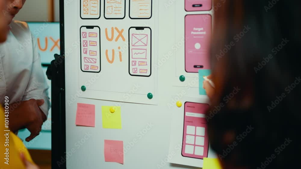 Poster Web designers collaborate on reviewing a smartphone application interface design, utilizing a whiteboard to discuss user experience and wireframe concepts