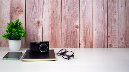 Mock up modern home decor with camera, Houseplant, Phone, Notebook, Glasses. Artist workspace with copy space for products display montage.