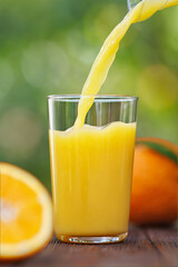 orange juice pouring into glass on table outdoors