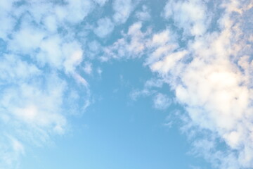 Bright blue sky filled with soft white clouds during the afternoon in a tranquil outdoor setting.