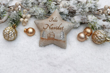 Estrella con la inscripción Feliz Navidad rodeada de bolas navideñas, ramas de abeto y nieve. La...