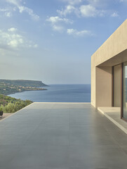 Fototapeta premium Modern terrace overlooking tranquil blue sea and hillside landscape in bright daylight