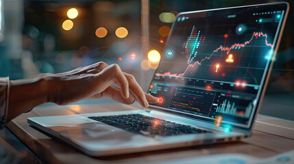 Close up of hands working on a laptop with a stock market chart on screen.