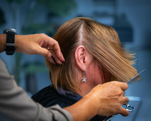 Fototapeta premium Hairdresser's hands cutting hair. Hairdresser cutting woman's hair. Short hair cut.