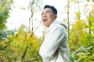 A young man with his arms crossed outdoors