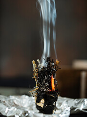 Black candle with herbs, wormwood, St. John's wort., tools for ritual concept photo. Dark witch core aesthetic. Old esoteric knowledge's concept. Selective focus