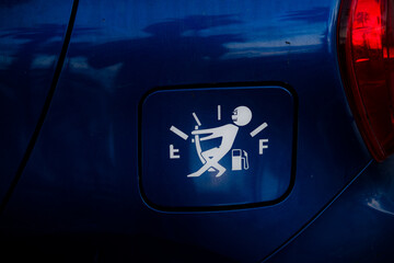 Tank window with a sticker of a man who pulls the gasoline arrow up