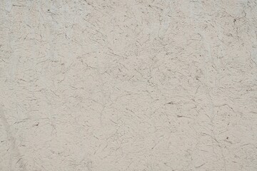 Fototapeta premium Textured Plaster Wall Background. A close-up of a textured plaster wall with an abstract rough surface. The neutral light beige color and irregular patterns create a natural and artistic backdrop. 