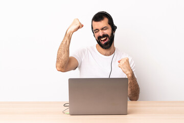 Telemarketer caucasian man working with a headset and with laptop celebrating a victory.