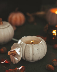 Handmade candles made of coconut and soy wax in a concrete, plaster candlestick with a wooden wick. Scented candle in a pumpkin-shaped candlestick. Selective focus