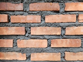 Obraz premium The new brick wall was constructed using red brick and glued with cement
