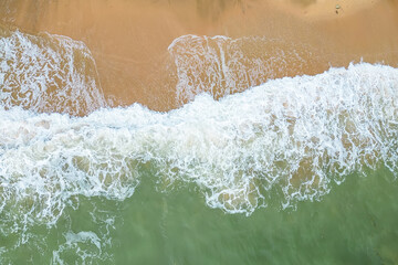 Aerial View of Ocean Waves Crashing on Sandy Beach.