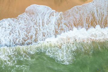 Aerial View of Ocean Waves Crashing on Sandy Beach.