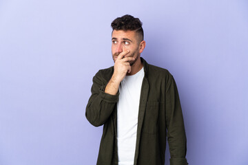 Caucasian man isolated on purple background having doubts and with confuse face expression