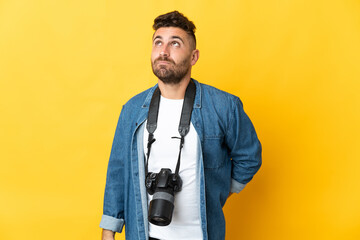 Photographer man isolated on yellow background and looking up