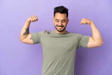 Young caucasian man isolated on purple background doing strong gesture