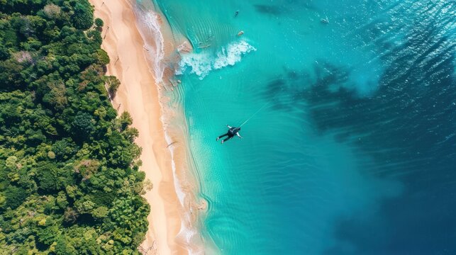 Aerial View of a Person Kiteboarding in the Turquoise Ocean near a Sandy Beach and Lush Green Forest