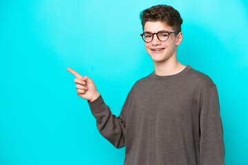 Teenager Russian man isolated on blue background pointing finger to the side
