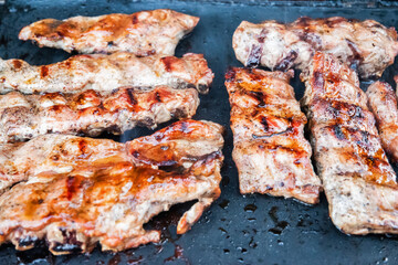 Grilling pork ribs on barbecue grill closeup