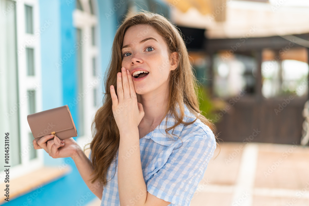 Poster Young redhead woman holding a wallet at outdoors whispering something