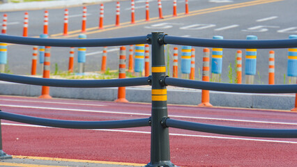Separated bicycle path alongside a road with safety barriers and bollards.