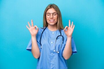 Young surgeon doctor woman isolated on blue background in zen pose