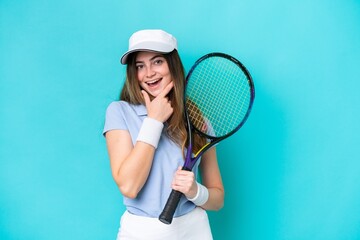 Young tennis player woman isolated on blue background happy and smiling