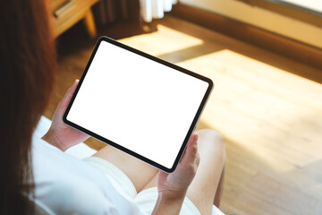 Top view mockup image of a woman holding digital tablet with blank desktop screen on the bed