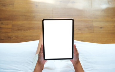 Top view mockup image of a woman holding digital tablet with blank desktop screen on the bed