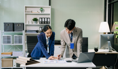 Two young Asian professionals engaged in teamwork and business discussions in office