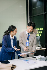 Two young Asian professionals engaged in teamwork and business discussions in office