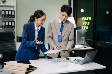 Two young Asian professionals engaged in teamwork and business discussions in office
