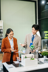 businesspeople standing neare table looking at model of building from residential project. Green business company and Solar Energy