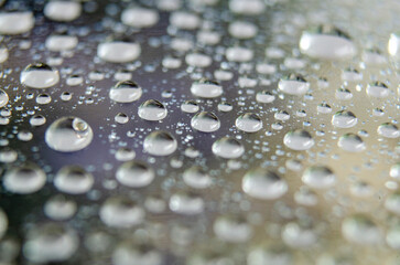 Raindrops gather, creating shimmering constellations on glass.