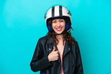 Young caucasian woman with a motorcycle helmet isolated on blue background giving a thumbs up gesture