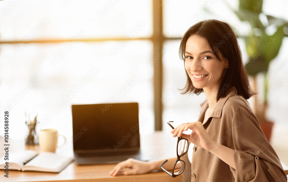 Aufkleber enjoying work. smiling female manager working on laptop and looking at camera sitting at her working