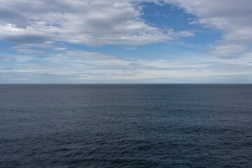 Obraz premium The horizon view of the sea and fluffy white clouds, against a bright blue sky, with little editing.