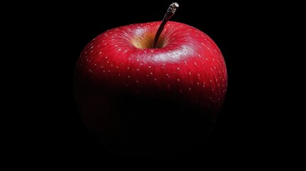 A Single Red Apple with a Stem Against a Black Background