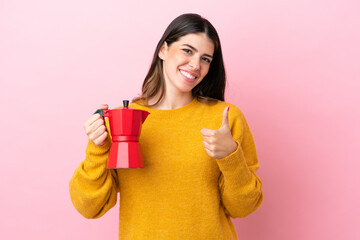 Obraz premium Young Italian woman holding a coffee maker isolated on pink background giving a thumbs up gesture