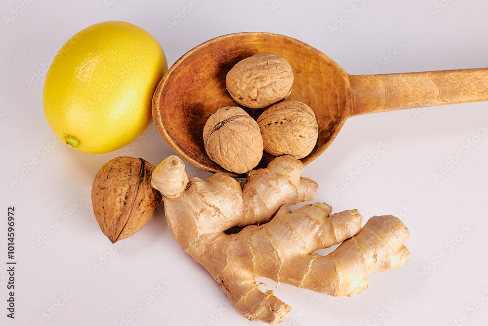 Wall mural ginger, nut in a large wooden spoon and lemon on a light background close-up, top view