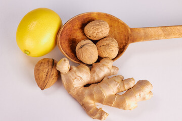 ginger, nut in a large wooden spoon and lemon on a light background close-up, top view