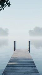 Fototapeta premium A tranquil wooden dock extending into a foggy lake, surrounded by calm waters and soft morning light.