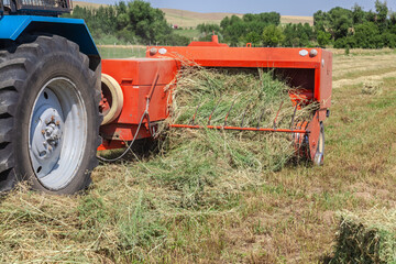 Close up of tractor baling hay using baler on summer day © kvdkz