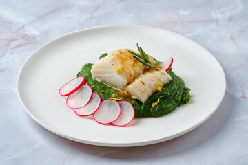 Delicate fish fillet served on a bed of vibrant spinach puree with fresh radish slices