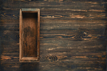 A rustic wooden box placed on a dark wooden table highlighting craftsmanship and texture