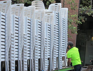 Plastic stackable chairs in a truck, a man loading and unloading