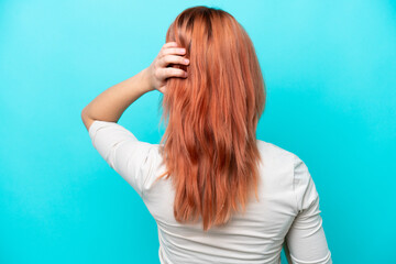 Obraz premium Young Russian woman isolated on blue background in back position and thinking