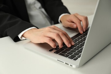 Businesswoman using laptop at white table indoors, closeup. Modern technology