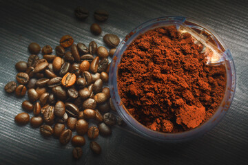 Coffee beans and ground into powder on a dark background.